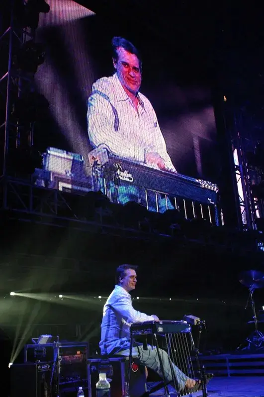 A man sitting on a stage in front of a large screen.